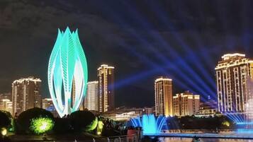 A cityscape at night with illuminated buildings and a prominent leaf-shaped structure.