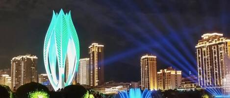 Un paisaje urbano nocturno con edificios iluminados y una estructura prominente con forma de hoja.