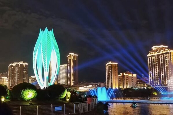 A cityscape at night with illuminated buildings and a prominent leaf-shaped structure. - Overseas Chinese Hotel (Nan'an)