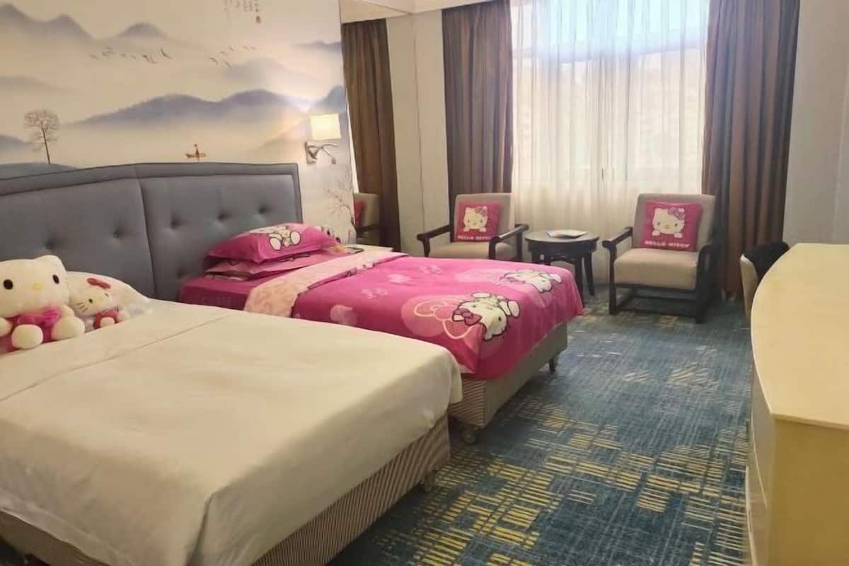 Une chambre d’hôtel avec deux lits, un bureau, une chaise et une vue sur l’extérieur.