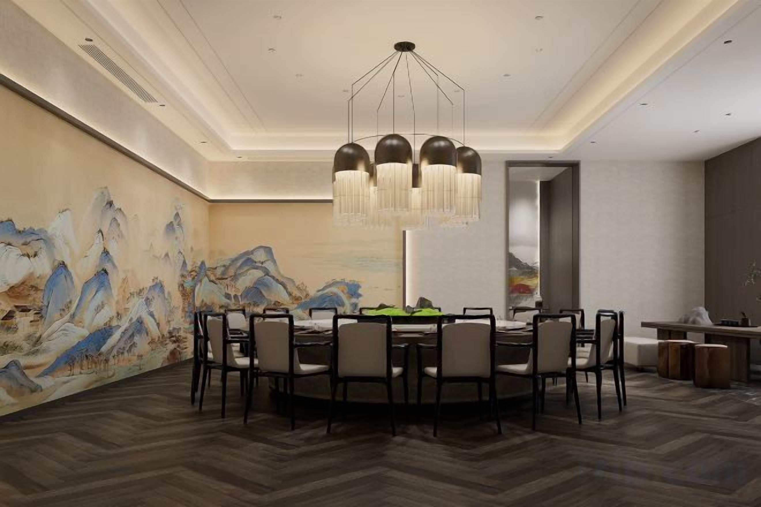 A dining area with a round table, chairs, a chandelier, and a wall with a painting.