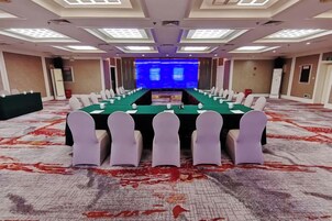 Una sala de conferencias con una larga mesa, sillas y un escenario al frente.