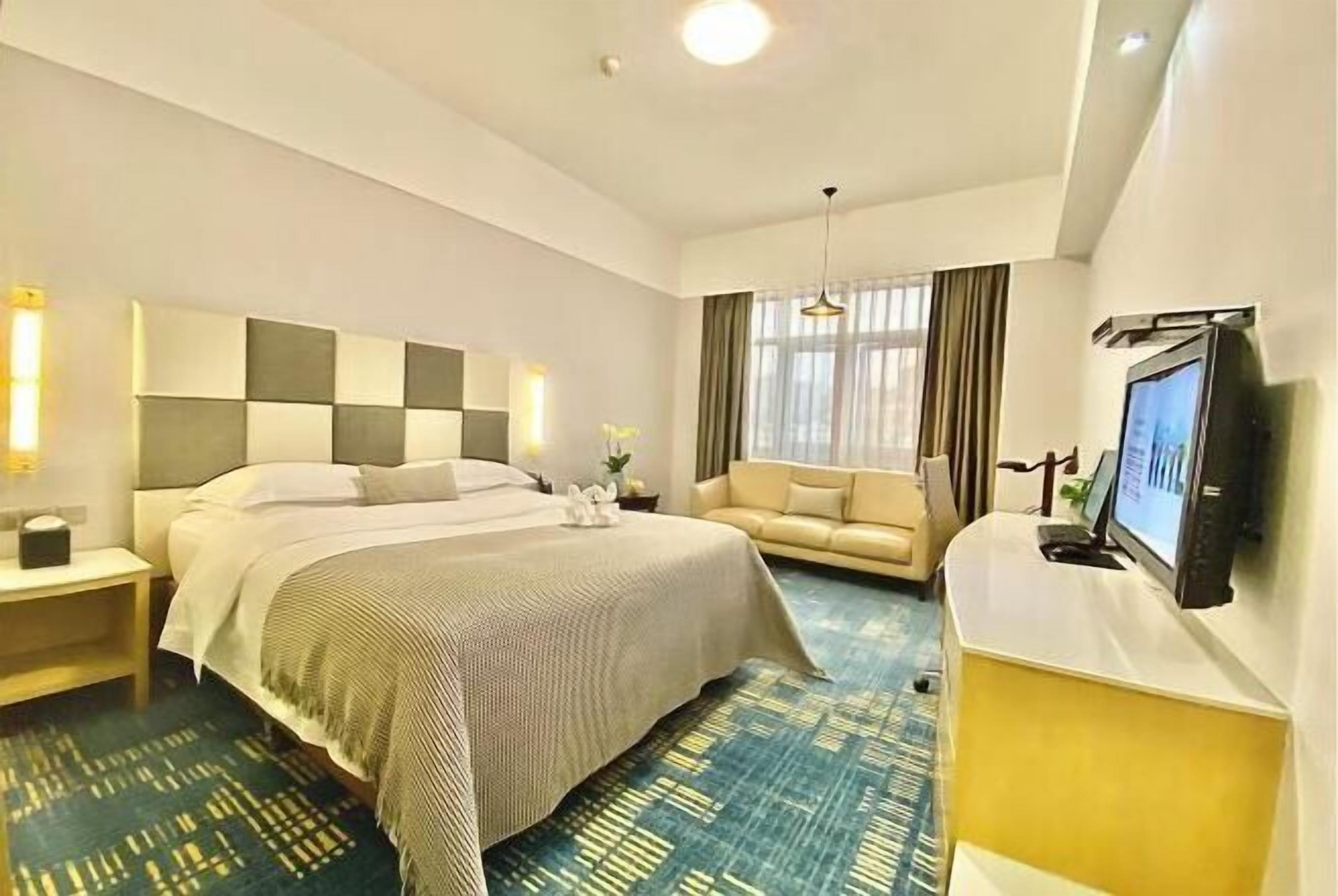 A hotel room with a bed, a sofa, a TV, and a desk.
