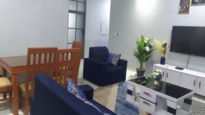 A living room with a dining table, two sofas, a TV, and a cabinet. - 3 Bed Flat - Sleeps 6 - Parking - Wifi (Adentan)