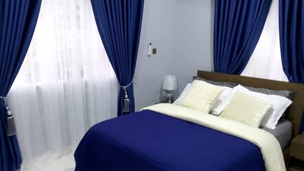 A hotel room with a bed, a nightstand, and a lamp. - 3 Bed Flat - Sleeps 6 - Parking - Wifi (Adentan)