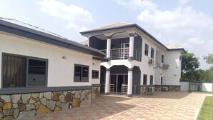 A two-story building with a stone facade and a tiled patio area. - 3 Bed Flat - Sleeps 6 - Parking - Wifi (Adentan)