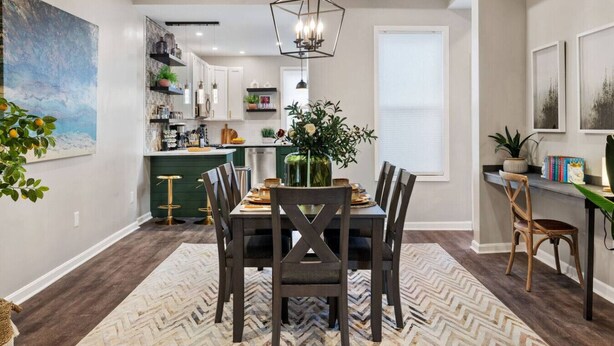 A modern kitchen with a central island, pendant lighting, and a dining area with a herringbone-patterned rug.