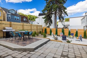 Un jardin avec un barbecue, du mobilier de jardin et une clôture en bois.