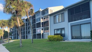 Un edificio residencial de varios pisos con balcones, césped y un sendero.