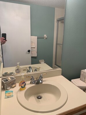 A bathroom with a sink, two faucets, a mirror, a towel rack, and toiletries.