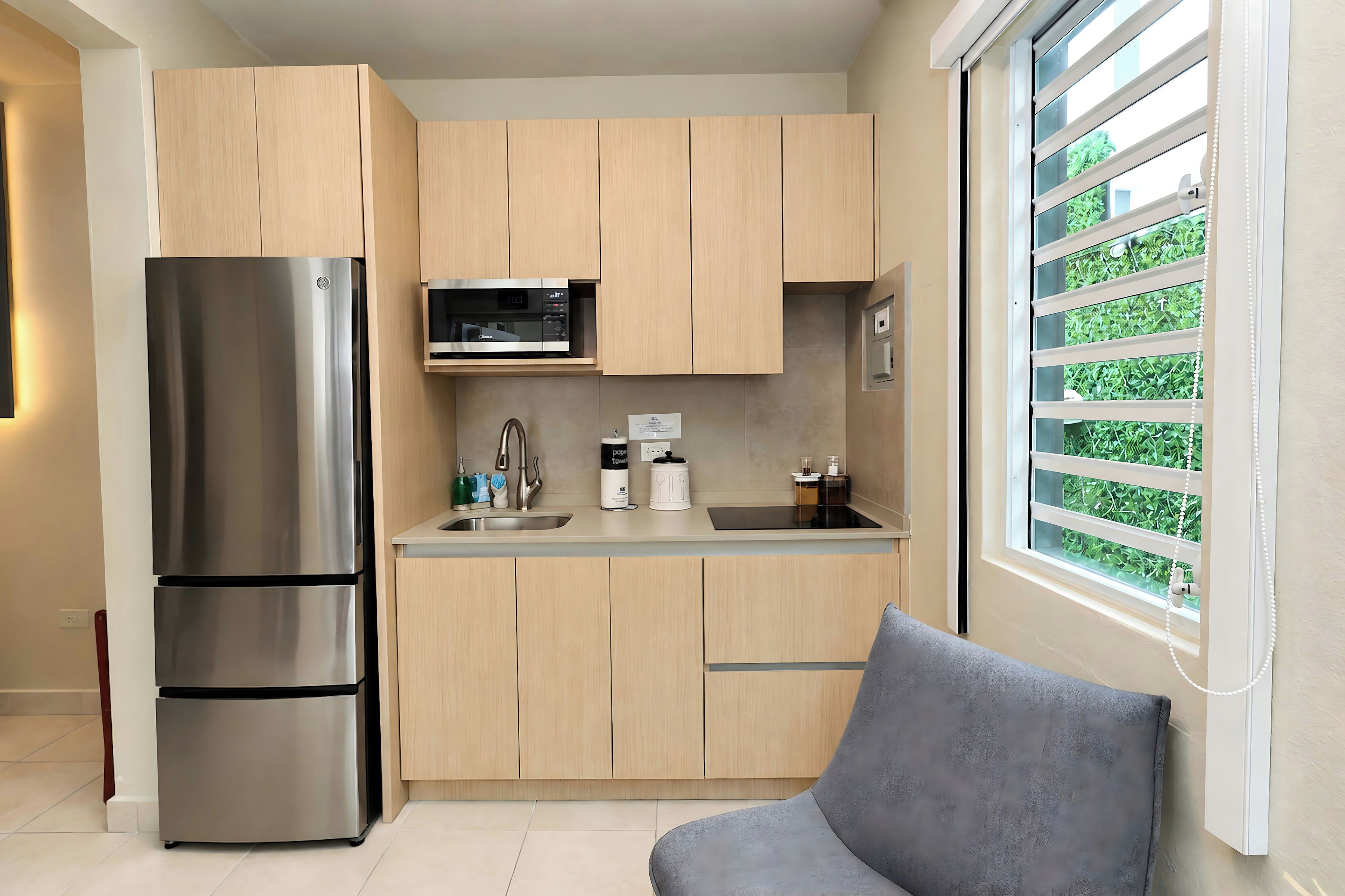 A modern kitchen with a stainless steel refrigerator, a microwave, and wooden cabinets.