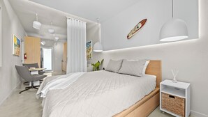 A modern bedroom with a large bed, a desk, and a chair. - THE BUOY (San Juan)