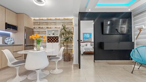 A modern kitchen with white cabinets, a microwave, and a dining area with white chairs. - THE BUOY (San Juan)