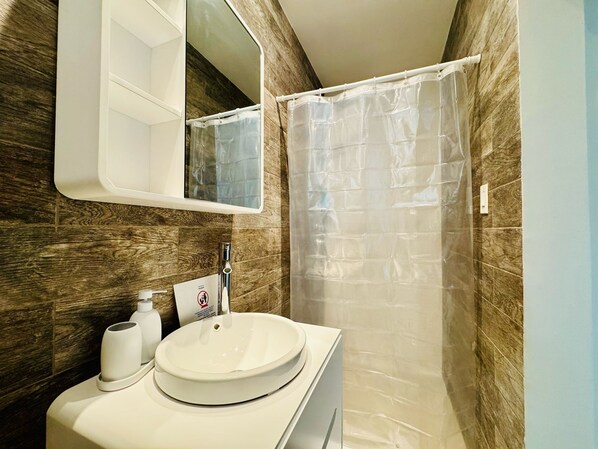 Un baño con pared de madera, un lavabo blanco, un espejo y una cortina de ducha.