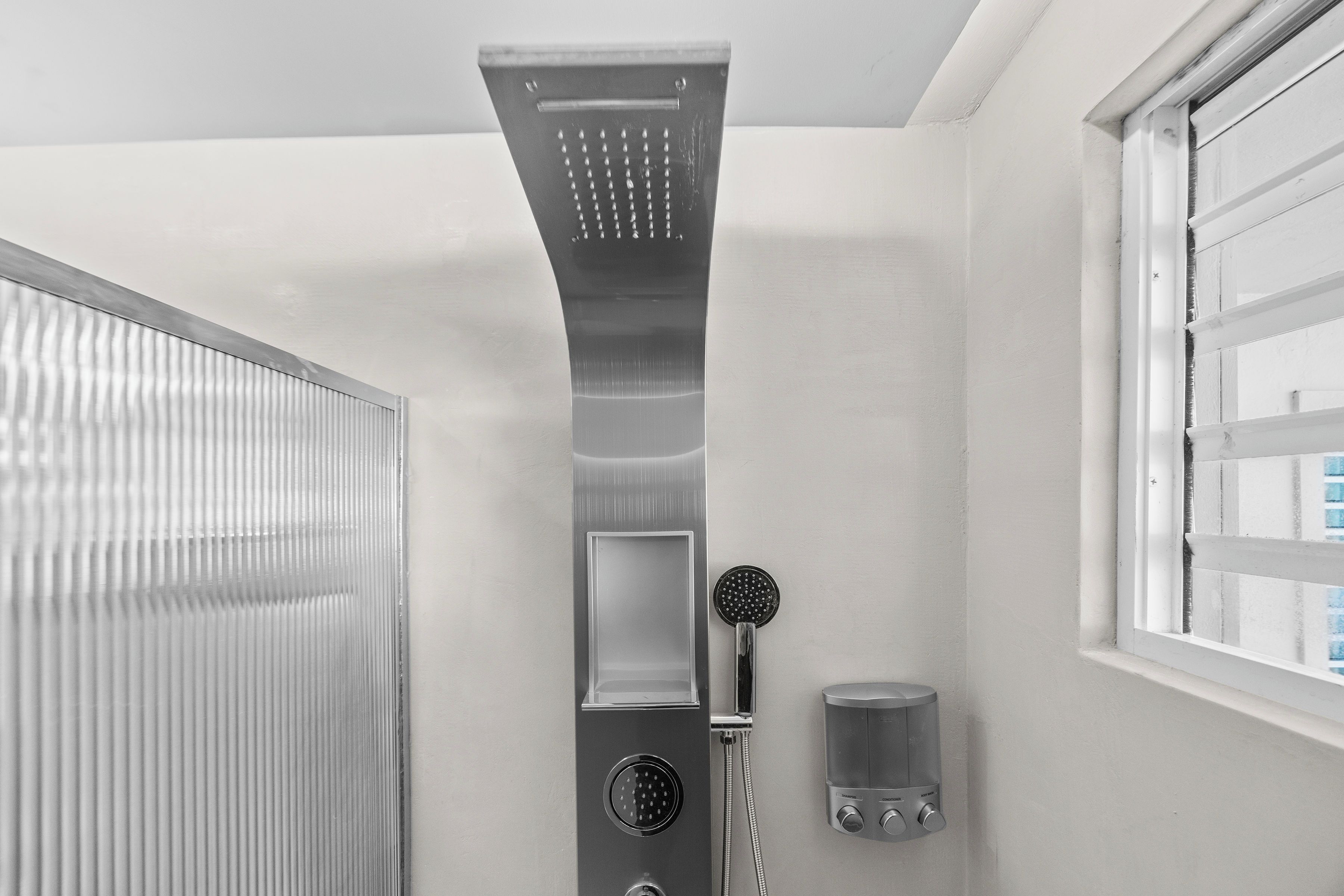 Un bagno moderno con doccia, finestra e asciugamani ad aria.
