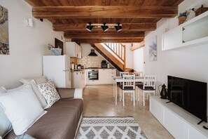Ein gemütliches Wohnzimmer mit einer Couch, einem Fernseher und einem Essbereich mit Stühlen und einem Tisch.