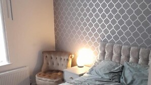 Una camera da letto con un letto, un comodino, una lampada e un termosifone.