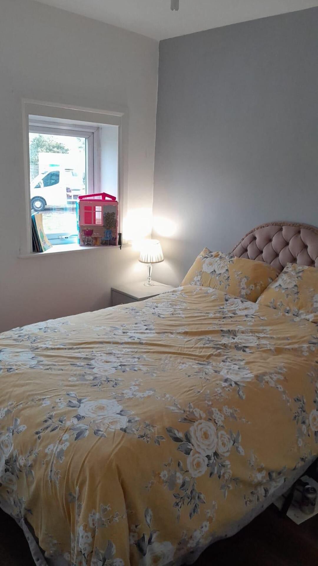 Une chambre à coucher avec un lit, une fenêtre et une table de chevet avec une lampe.