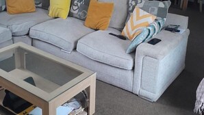 Un soggiorno con un divano componibile, un tavolino da caffè e una zona pranzo con sedie.