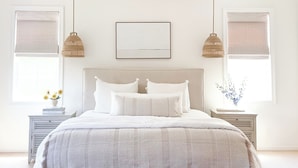 Un dormitorio con una cama grande, dos mesitas de noche, una lámpara colgante y un cuadro enmarcado en la pared.