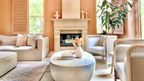 Una sala de estar con chimenea, sofás, una mesa de centro y una planta grande.