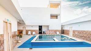 Ein Poolbereich mit einem blauen Pool, weißen Liegestühlen und einer Steinmauer.