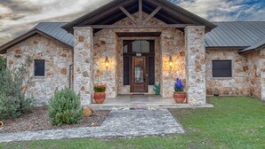 A stone house with a dark brown door, numbered 205, and two potted plants on either side. - La Mansion on The Frio - Pickleball Court, Pool (Concan)