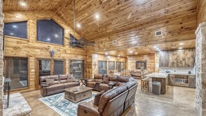 A spacious log cabin interior with a large leather sofa, a dining area, and a kitchen. - La Mansion on The Frio - Pickleball Court, Pool (Concan)