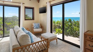 A balcony with a sofa, a chair, and a TV. - Villa Caona, Quintessential Caribbean Oceanfront Home (Providenciales)
