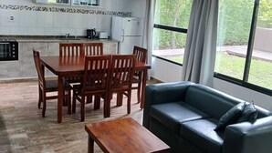 Ein großzügiger Wohnbereich mit Esstisch und Stühlen, einer Couch und einer Küche mit Kühlschrank und Mikrowelle.