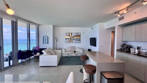 Una sala de estar moderna con un sofá, una mesa de centro y vista al mar a través de amplios ventanales.