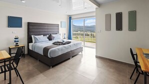 Una camera da letto moderna con un letto, una scrivania e un balcone con vista.