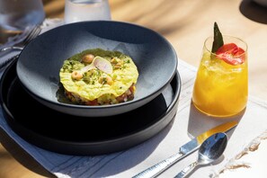 Un plato de comida con un vaso de bebida sobre una mesa.