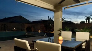 Un patio al aire libre con piscina, mobiliario y vistas del paisaje circundante.