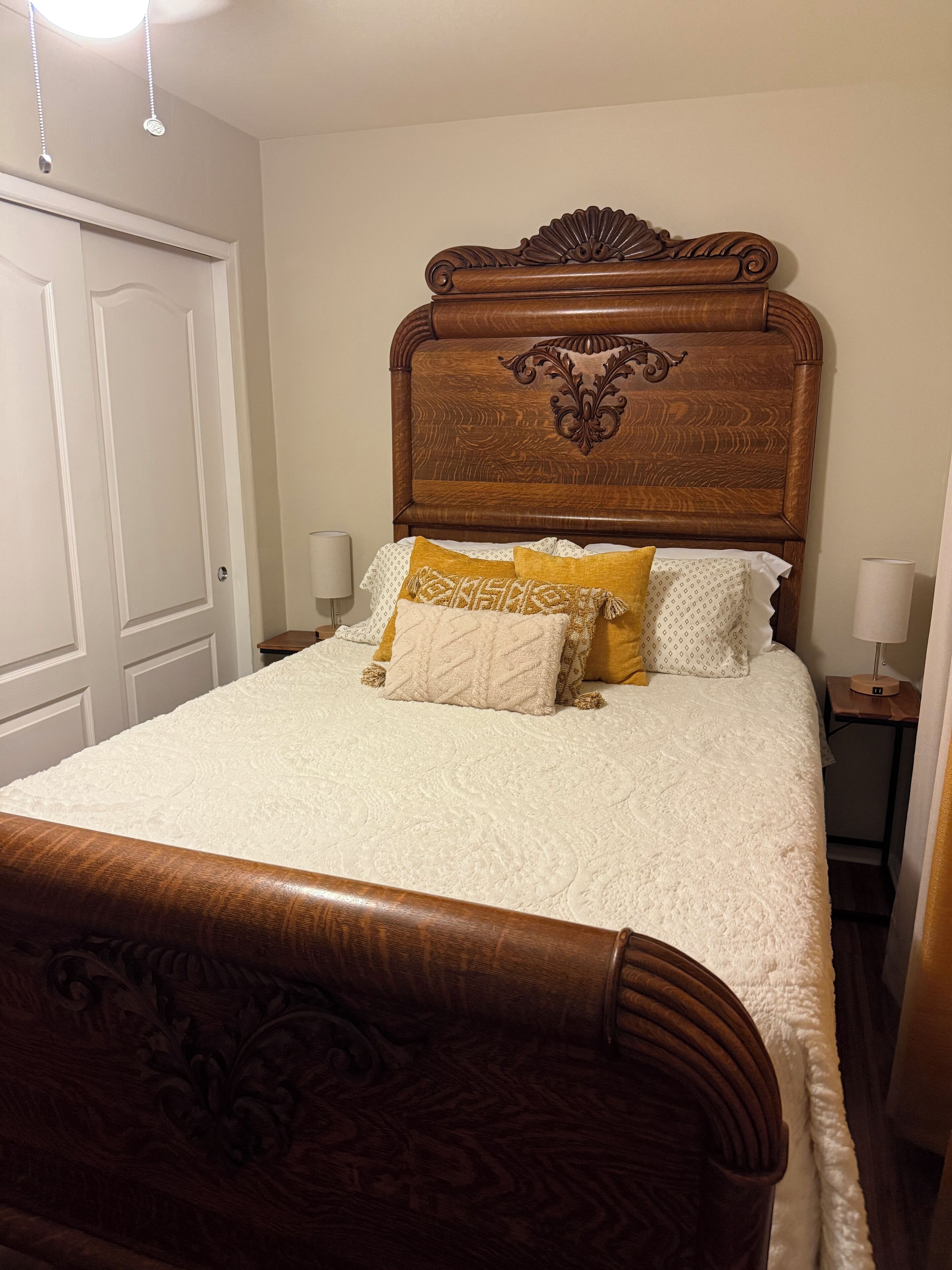 A neatly made bed with a wooden headboard, white bedding, and decorative pillows.