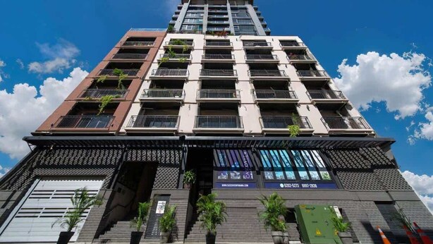 Un edificio de varios pisos con balcones, una escalera y una dirección web en la fachada.