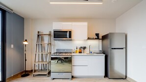 Eine kompakte Küche mit integriertem Mikrowellenherd, Gasherd und einem Edelstahl-Kühlschrank.