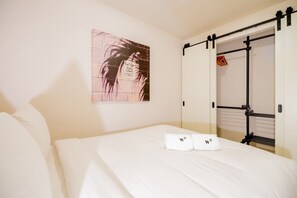 Une chambre d’hôtel avec un lit, une œuvre d’art accrochée au mur et une porte de placard coulissante.