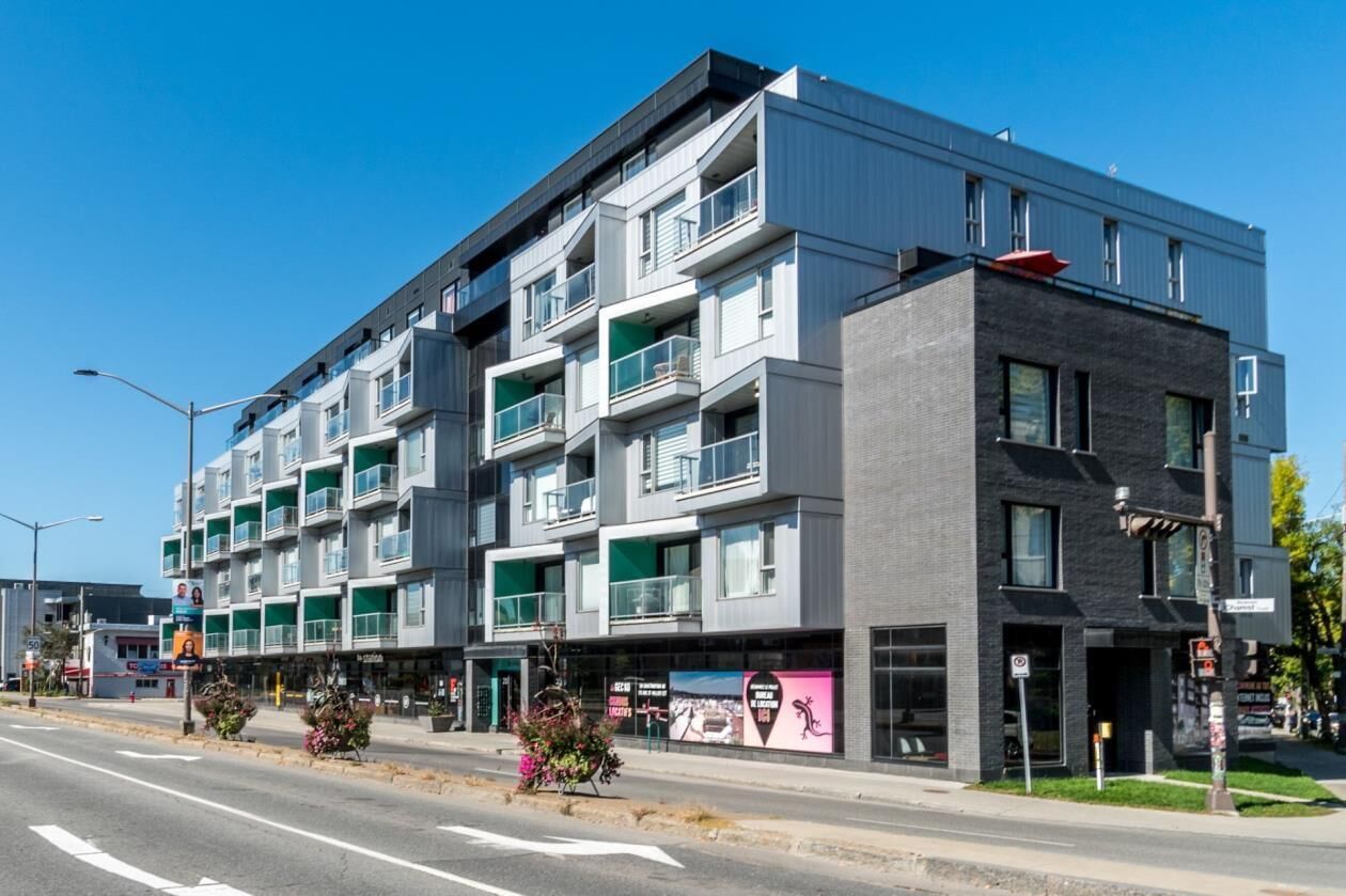 A modern multi-story building with balconies, a mix of window styles, and a flat roof.