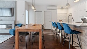 A modern kitchen with a wooden island, blue bar stools, and pendant lighting. - Le Saphir, NEW, Spacious 2-bedroom Condo, Downtown Quebec City 5*, Quebec City (Québec)