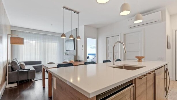 A modern kitchen with a central island, pendant lighting, and a view to the living area. - Le Saphir, NEW, Spacious 2-bedroom Condo, Downtown Quebec City 5*, Quebec City (Québec)
