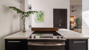 Una cocina moderna con una isla central, armarios negros y un ventanal grande.