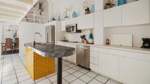 A modern kitchen with white cabinets, a grey countertop, and a yellow-tiled island.