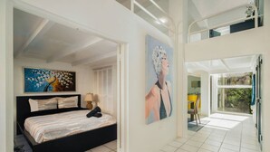 A bedroom with a bed, a painting, and a view of a balcony.