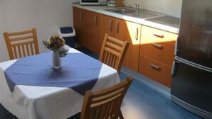 A compact kitchen with a dining table, chairs, and a refrigerator.