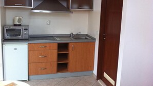 A compact kitchen with a microwave, sink, and wooden cabinets.