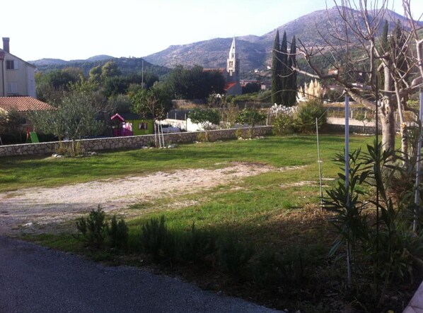 A residential area with a grassy yard, a stone wall, and a building with a red roof.