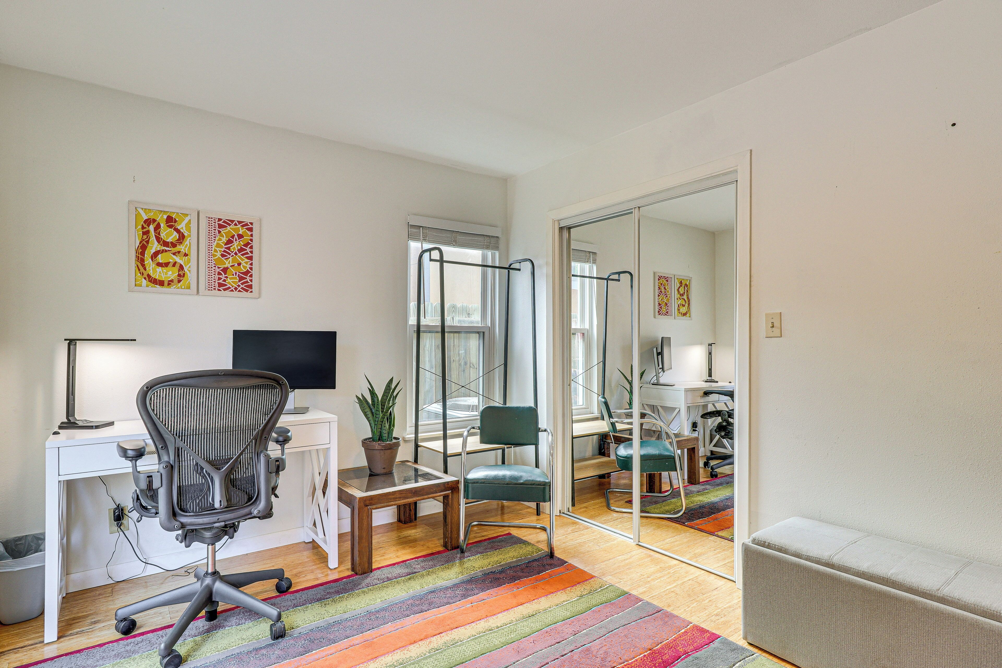 A modern office space with a desk, office chair, computer, and a potted plant.