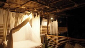Een kamer met hemelbed, houten meubels en rieten dak.