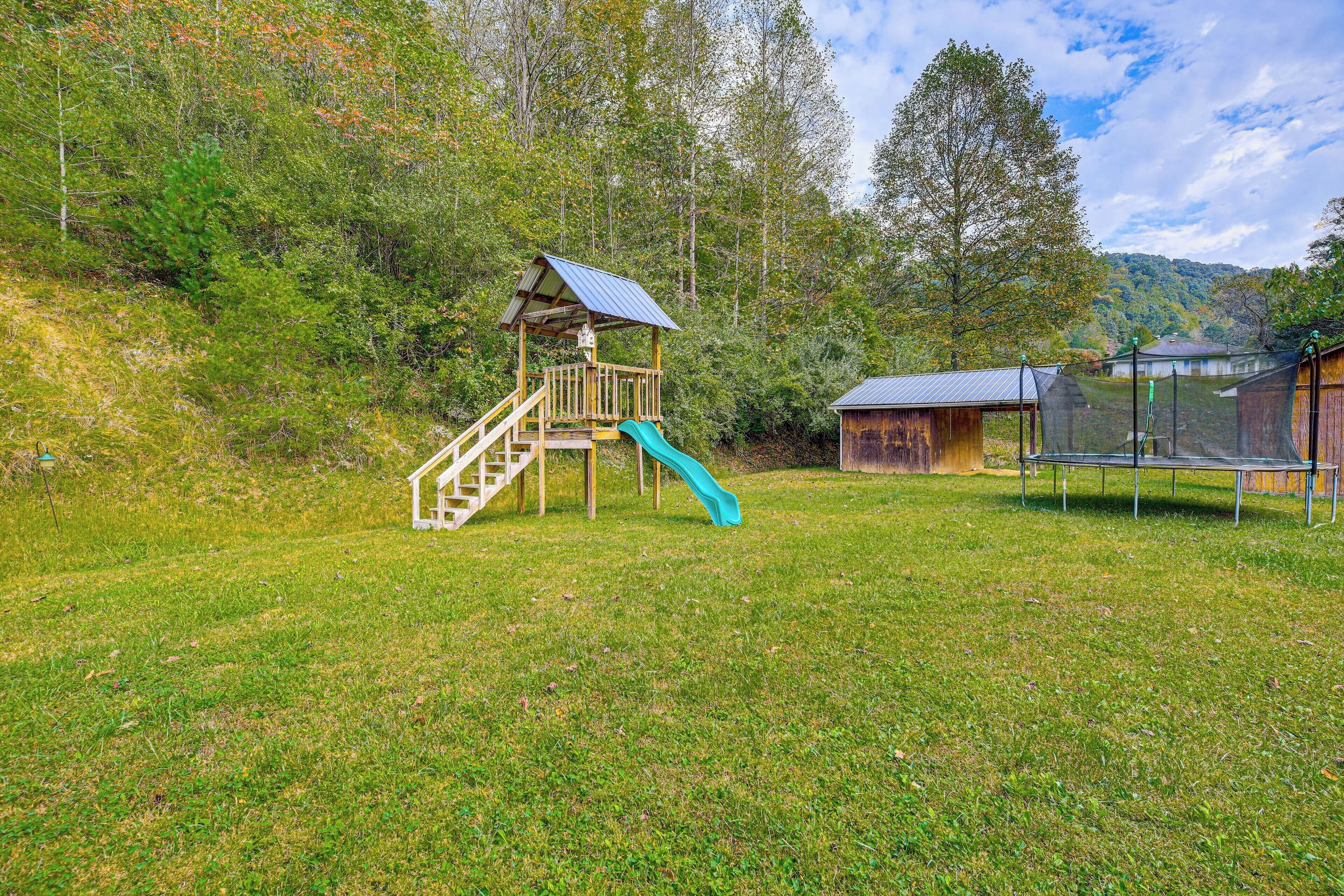 Ein Spielplatz mit Rutsche, einer kleinen Holzkonstruktion und einem Trampolin.